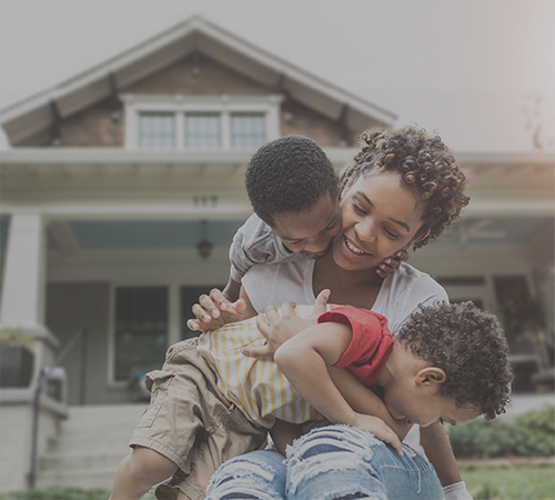 Mother with two children in front of house