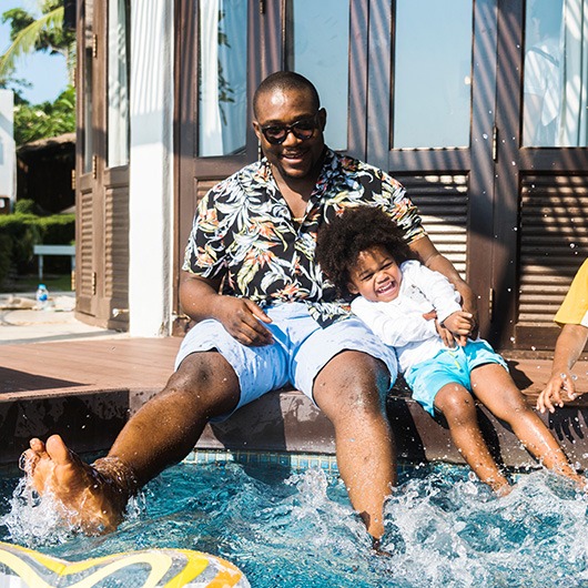 Man and young child splashing in swimming pool